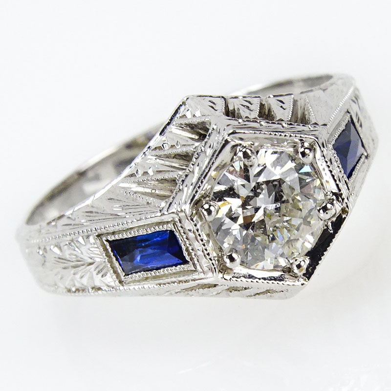 Circa 1930 Art Deco Approx. .90 Carat Round Cut Diamond and 18 Karat White Gold Engagement Ring with Calibre Cut Sapphire Accents.