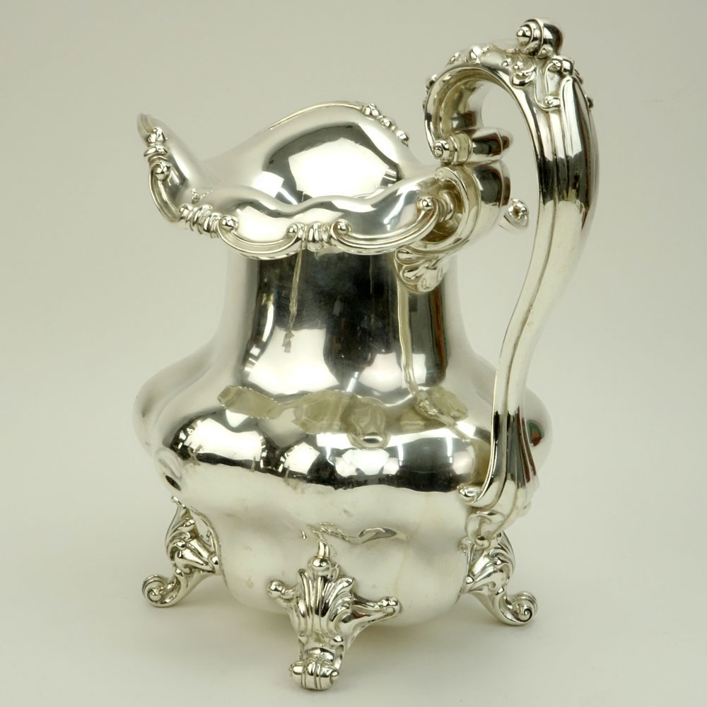 Large Durgin Sterling Silver pitcher. Features foliate handle and scroll feet.