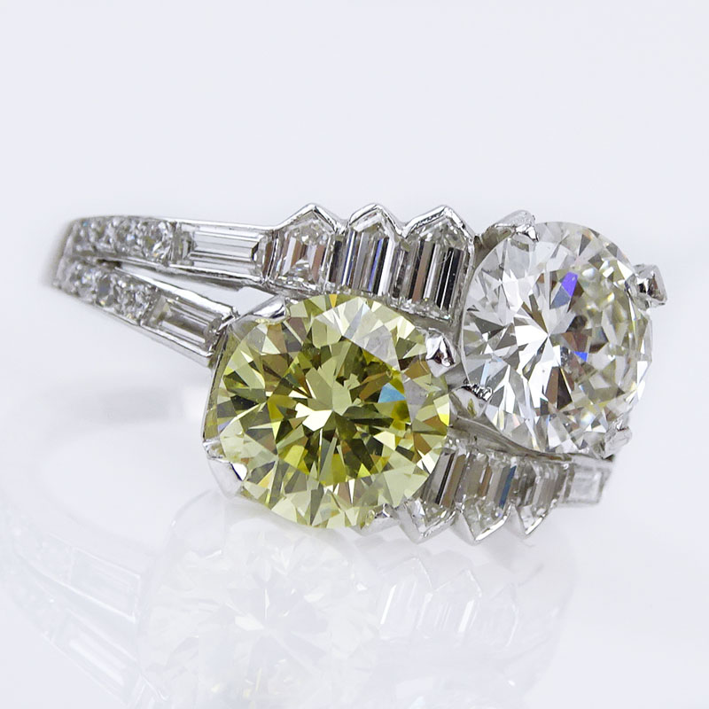 1.85 Carat Round Brilliant Cut Fancy Intense Yellow Diamond and an Approx. 1.70 Carat Round Brilliant Cut Diamond and Platinum Two Stone Crossover Ring.