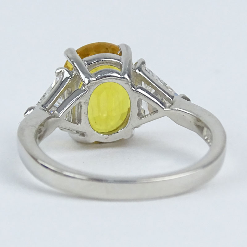 Approx. 4.33 Carat Oval Cut Yellow Sapphire, .78 Carat Trillion Cut Diamond and Platinum Ring. 