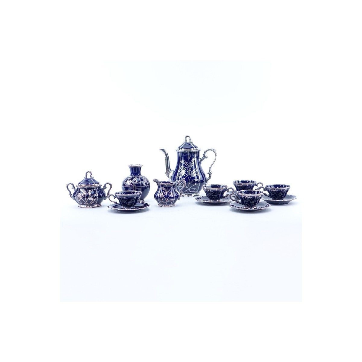 Thirteen (13) Piece German Cobalt Blue Porcelain and Pure Silver Tea Set. Includes: five cups, four saucers, creamer, covered sugar, vase, and tea pot.
