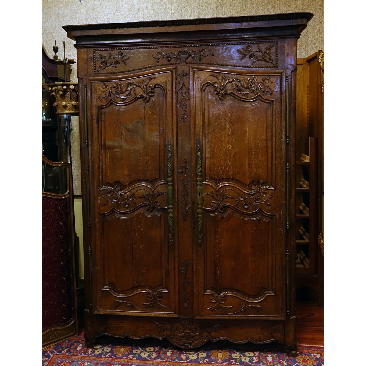 Early 19th Century Louis XV Style Carved Oak Armoire with Bronze Mounts. Carved with baskets, urns, flowers and leaf work throughout the surface.