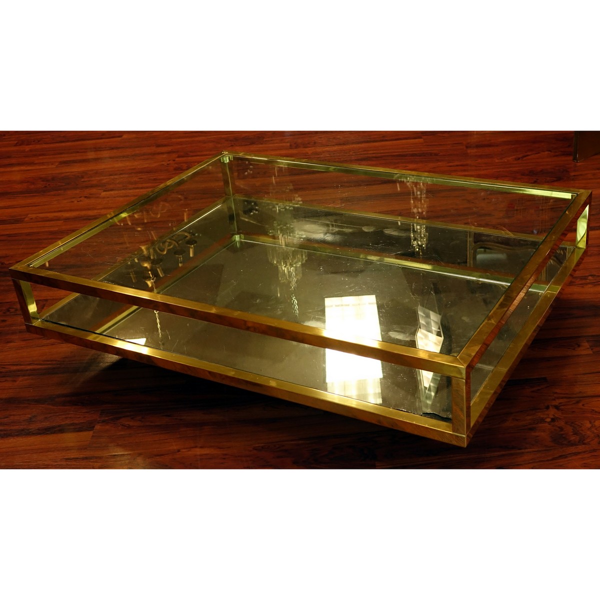 Mid Century Modern Mirrored and Glass Top Coffee Table. Scratches to brass, scratches to glass top, and mirror has a loss to corner.
