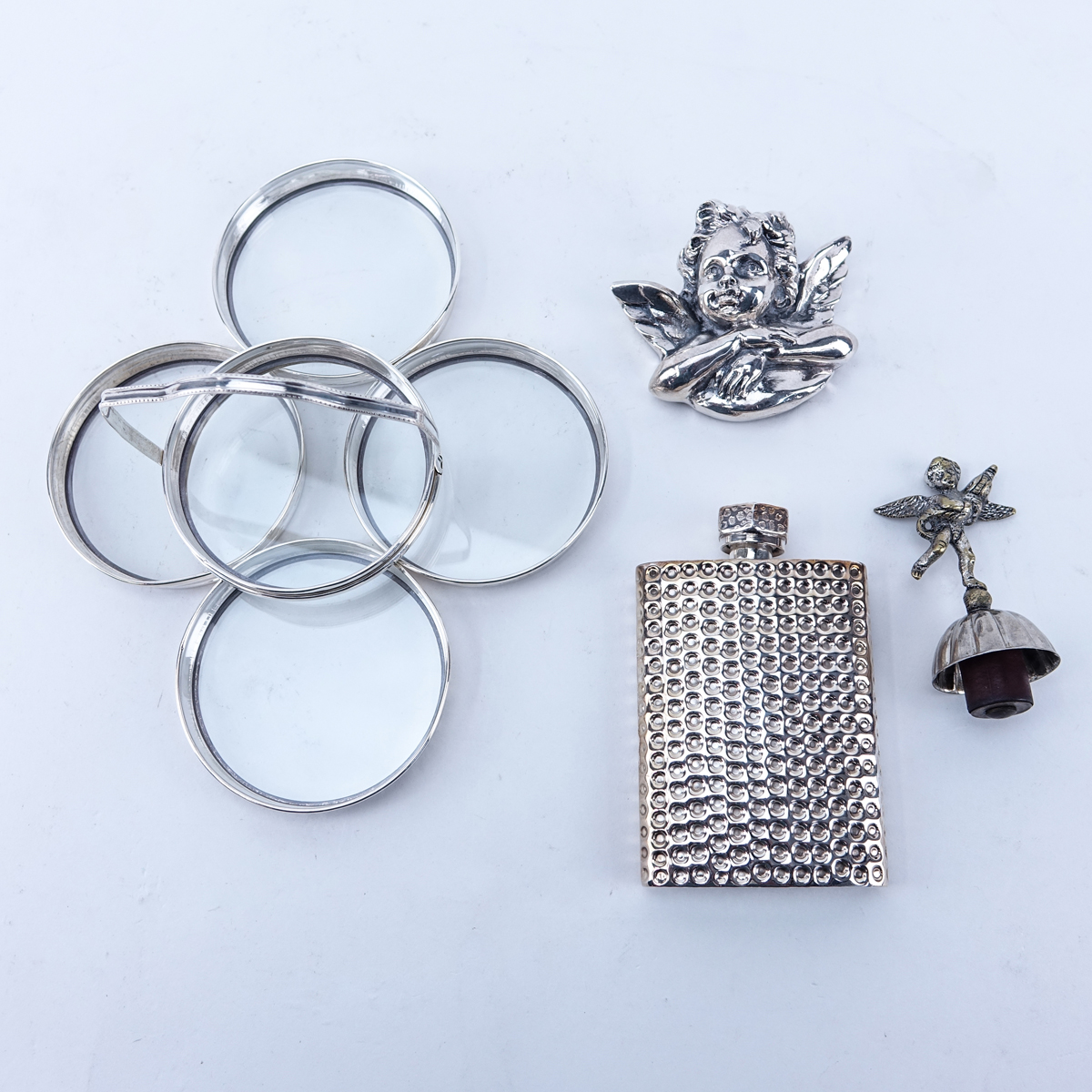 Lot of Silver Accessories. Includes: Mexican silver flask, 5 pieces silver and glass coaster set, Henryk Winograd sterling clad paperweight, silver plate figural wine stopper.