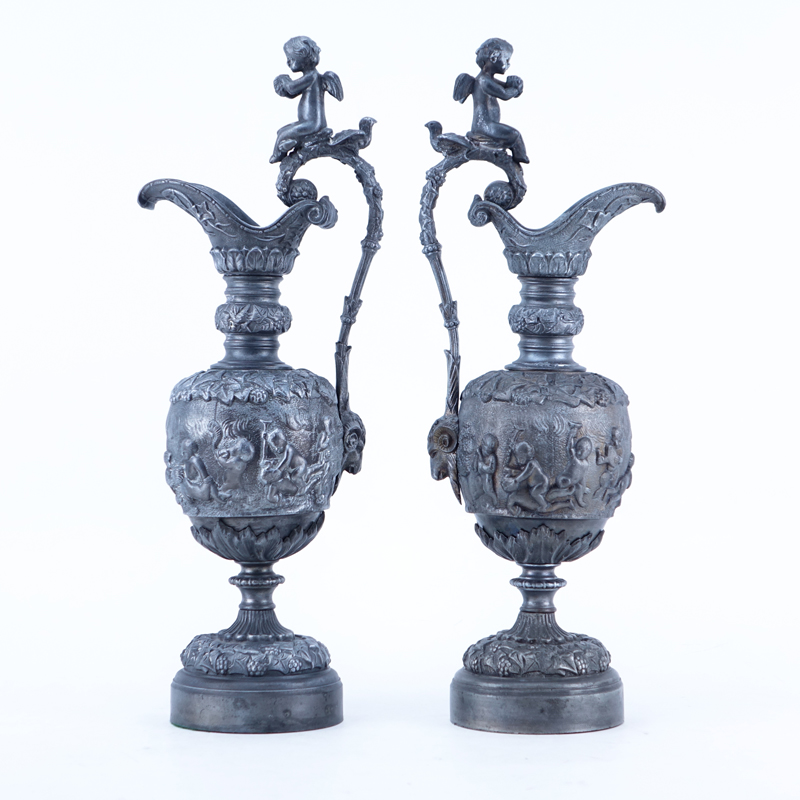 Pair of 20th Century Neoclassical Style Metal Ewers with Bacchanalian scenes. Rubbing otherwise good condition.