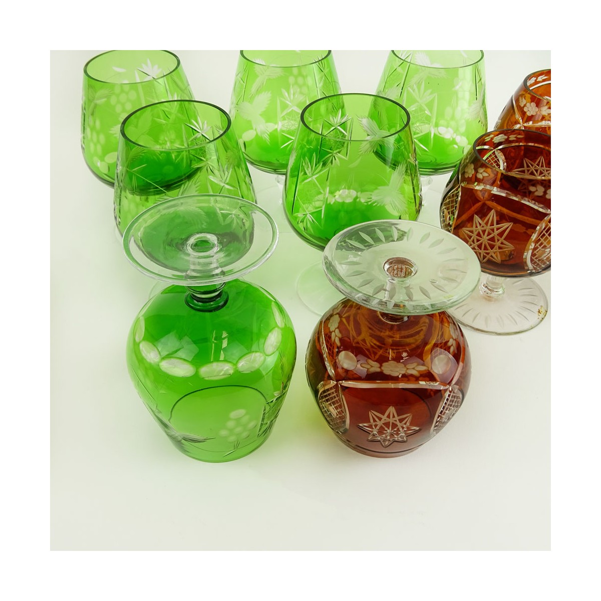 Lot of 9 Bohemian Cut Glass Brandy glasses in Green and Deep Orange. Various stems. Measure 4-1/2" 